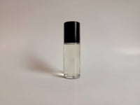 Clear glass roller bottle with black cap on a light gray background